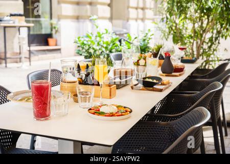Ein wunderschön gestalteter Brunch-Tisch im Freien mit einer Vielzahl von Gerichten und Getränken, einschließlich Salaten, Suppen, frischen Säften und Vorspeisen. Die Stockfoto
