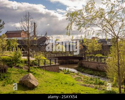 River Medlock fließt durch den Mayfield Park und die Ardwick Green Gegend von Manchester in der Ferne. Stockfoto