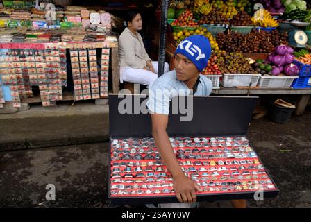 Mann, der gefälschte Designersachen verkauft - teure Designer-Uhren auf einem Straßenmarkt. Er ist besorgt, dass die Behörden auf dem Markt sind. Der Deckel seines Tabletts lässt sich herunterklappen und ermöglicht es ihm, sich sehr schnell weiterzubewegen. Ubud, Insel Bali, Indonesien 27. Januar 2006. 2000er Jahre HOMER SYKES Stockfoto