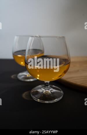 Zwei Gläser goldener Whiskey auf einem dunklen Tisch, elegante Stimmung. Stockfoto