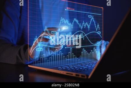 Eine Person analysiert Diagramme auf einem Laptop und verwendet virtuelle Elemente für die Interaktion. Hintergrund der Unternehmensfinanzierung Stockfoto