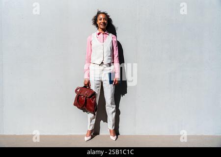 Schöne schwarze Geschäftsfrau mittleren Alters in elegantem Anzug, die durch die Stadt schlendert - Corporate hispanic Erwachsene Frau mit stilvoller formeller Kleidung Stockfoto