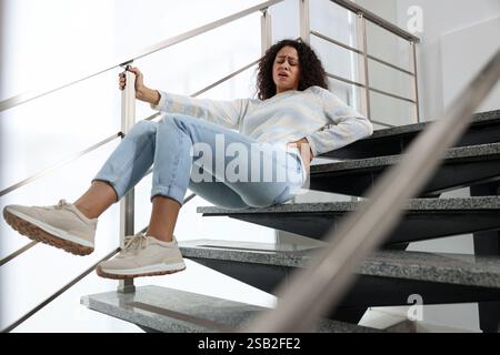 Verletzte Frau auf Treppen im Gebäude nach dem Sturz. Gefährlicher Unfall Stockfoto