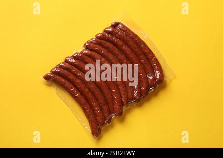 Packung geräucherte Würstchen auf gelbem Hintergrund, Draufsicht Stockfoto