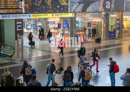 Reisende im Bahnhof Roma Termini in Italien. Rom, Italien - 26. Januar 2025: Im Bahnhof Termini, dem wichtigsten Eisenbahnknotenpunkt der Hauptstadt, bewegen sich die Reisenden mit Trolleys und Koffern, die vor der Abfahrt auf den Bahnsteig warten. Verschiedene Geschäfte bieten die Möglichkeit, vor der Reise etwas einzukaufen. Rom RM Italien Copyright: XGennaroxLeonardix Stockfoto