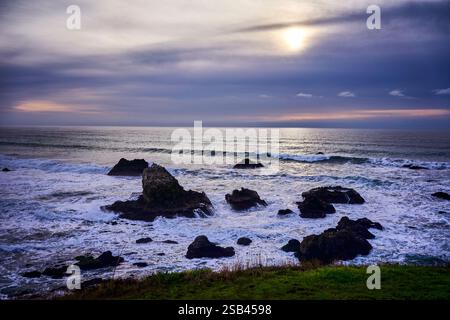 Sonnenuntergang während des Sturms, als Wellen gegen die felsige Küste krachen Stockfoto