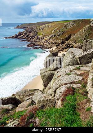 Granitklippen über dem sandigen Porth Chapel Strand an der südkornischen Küste in der Nähe von Porthcurno an einem sonnigen Septembertag, Cornwall, England, Großbritannien Stockfoto
