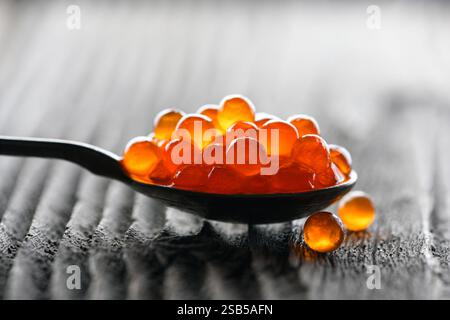 Nahaufnahme von rotem Kaviar in einem Metalllöffel auf Holztisch. Makroaufnahme. Lebensmittelfotografie Stockfoto
