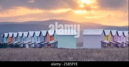 Eine atemberaubend malerische Szene mit einer Reihe von farbenfrohen Strandhütten vor einem ruhigen, atemberaubenden Sonnenuntergangshimmel Stockfoto