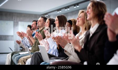 Ein erfolgreiches Business Seminar lässt verschiedene Zuschauergruppen klatschen und beobachten Stockfoto