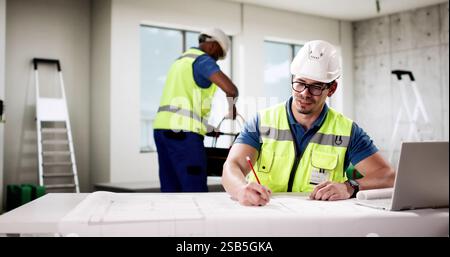 Der professionelle Vorarbeiter verwendet einen Laptop, um auf der Baustelle zu kommunizieren. Stockfoto