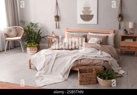 Großes Bett mit Bettwäsche in Mokka-Mousse-Schatten drinnen. Stilvolle Inneneinrichtung des Schlafzimmers in trendigen Farben von 2025 Jahren Stockfoto