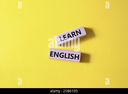 Symbol Englisch lernen. Holzblöcke mit Wörtern lernen Englisch. Schöner gelber Hintergrund. Business and Learn English Concept. Kopierbereich. Stockfoto