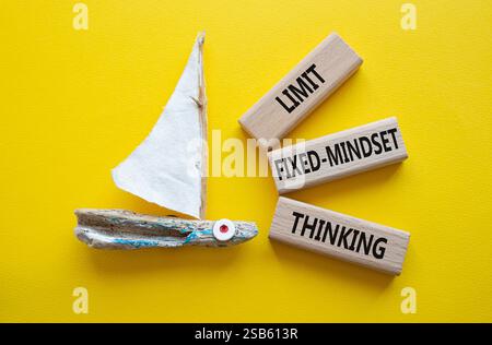 Begrenzen Sie das Denksymbol für feste Denkweisen. Konzeptworte beschränken das Denken auf Holzblöcke. Schöner gelber Hintergrund mit Boot. Business-Konz Stockfoto