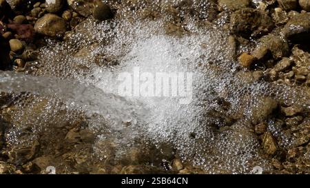 Fließendes Wasser, das über Felsen spritzt, Blasen an der kleinen Strömungskante erzeugen Stockfoto