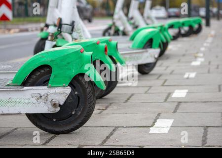 Mehrere Elektroroller parkten auf dem Bürgersteig. Motorroller sind grün und haben große Räder. Stockfoto