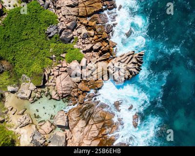 Blick aus der Vogelperspektive auf Anse Caiman auf der Insel La Digue auf den Seychellen mit zerklüfteten Granitfelsen, klaren flachen Pools und lebendiger grüner Küstenvegetation A Stockfoto