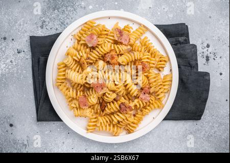Carbonara-Pasta mit knusprigen Speckstückchen und Parmesankäse auf einem Teller. Grauer Hintergrund. Draufsicht. Stockfoto