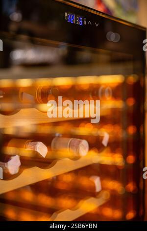 Ein eleganter Weinkühler mit einer transparenten Glastür, die eine elegante Sammlung von Weinflaschen präsentiert, perfekt in einem modernen Restaurant platziert. Stockfoto