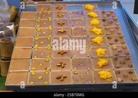 Präsentation traditioneller thailändischer Pudding-Desserts, bekannt als „Khanom Mo Kaeng“, ordentlich in quadratischen Tabletts mit verschiedenen Belägen, einschließlich Ginkgo-Nüssen, Stockfoto