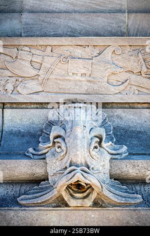 WASHINGTON DC – das John Paul Jones Memorial verfügt über in Stein gehauene Fischköpfe, die als dekorative Wasserauslässe am Sockel des Sockels dienen. Die Bronzestatue, die 1912 vom Bildhauer Charles Henry Niehaus und dem Architekten Thomas Hastings geschaffen wurde, zeigt den Marineheld des Unabhängigkeitskrieges in Offizierskleidung aus der Zeit. Der Marmor-Pylon enthält militärische Symbole und ein Relief, das Jones zeigt, wie er die erste amerikanische Flagge auf einem US-Kriegsschiff hisst, neben seiner berühmten Erklärung „Kapitulation? Ich habe noch nicht angefangen zu kämpfen!" Stockfoto