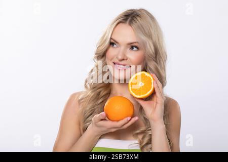 Eine Frau, die frische Orangen in einem hellen und fröhlichen Studio-Setting voller Farben hält Stockfoto