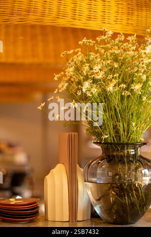 Besteck, Serviettenhalter und Vase mit Blume auf einem Holztisch in einem trendigen Café Stockfoto