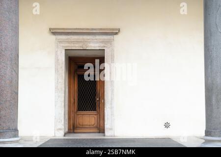 Alte Holztür an einer weißen Putzwand eines mittelalterlichen Steingebäudes zwischen zwei grauen Säulen Stockfoto