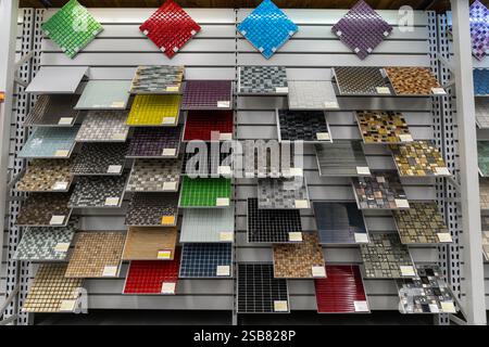 Muster von Mosaikfliesen aus Keramikfliesen, einschließlich verschiedener Farben und Texturen, die auf Holzregalen ausgestellt sind, ideal für den Einsatz in architektonischen Desi Stockfoto