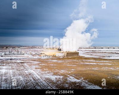 Kraftwerk unter winterlichem Himmel, das Strom erzeugt und Dampf aus Turbinen erzeugt, die Energie erzeugen. Stockfoto