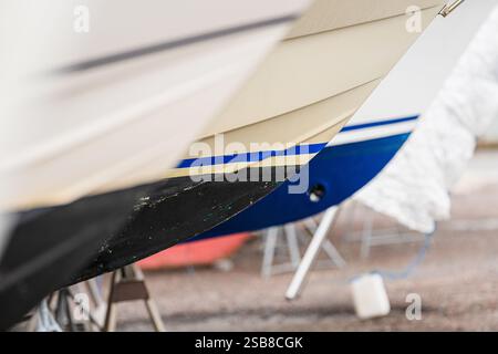 Schiffsrümpfe auf Ständen in der Werft mit verschiedenen Farbschemata Stockfoto