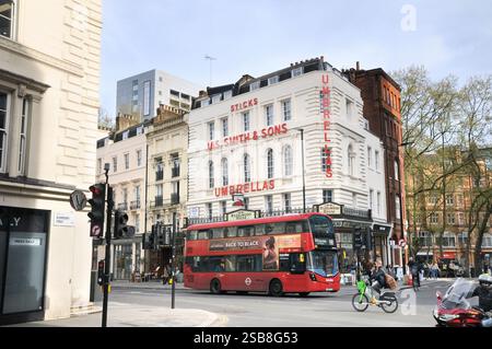 Roter Doppeldeckerbus vorbei an dem berühmten James Smith and Sons, Londons ältestem Dachdeckerladen, in der New Oxford Street. Jas. Smith & Sons Stockfoto