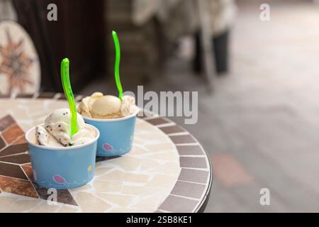 Zwei Portionen Eis in Pappbechern auf einem Tisch in einem Café draußen Stockfoto