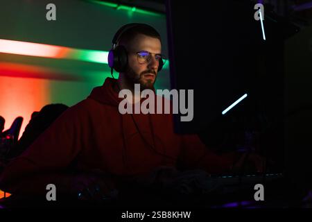 Spieler, der an einem Spielwettbewerb teilnimmt, vor einem Computermonitor sitzt und Videospiele spielt. Stockfoto