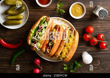 Hot Dogs mit verschiedenen Belägen auf hölzernem Hintergrund. Draufsicht, flach Stockfoto