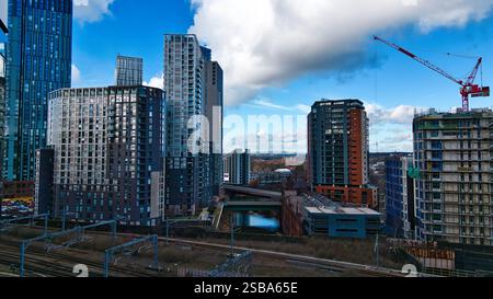 Wohnhochhäuser und eine Baustelle unter teilweise bewölktem Himmel, aus erhöhter Perspektive mit Eisenbahngleisen im f Stockfoto