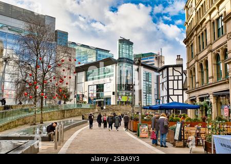 Eine Straßenszene in der Stadt mit einem Harvey Nichols Kaufhaus, moderner und historischer Architektur, Fußgängern, Sitzgelegenheiten im Freien und einem Baum, der mit wi geschmückt ist Stockfoto
