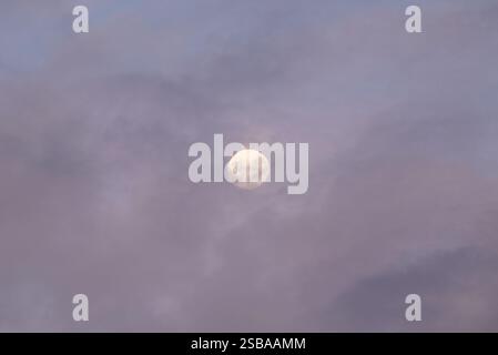 Vollmond durch Wolken und Nebel in einem grauen Himmel Stockfoto