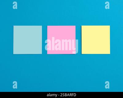 Leere farbige Notizpapiere auf blauem Hintergrund. Stockfoto