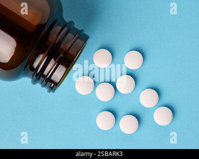 Weiße medizinische Pillen und Tabletten verschüttet aus einer Drogenflasche. Stockfoto