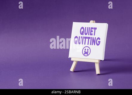 Das Wort leise hört auf einer Staffelei auf violettem Hintergrund auf. Resignment und Business Quiet Beenden Konzept. Stockfoto