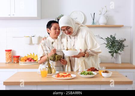 Mama und Kinder bereiten Ketupat Lebaran für Eid Al Fitr Muslim Hari Raya Feier vor Stockfoto