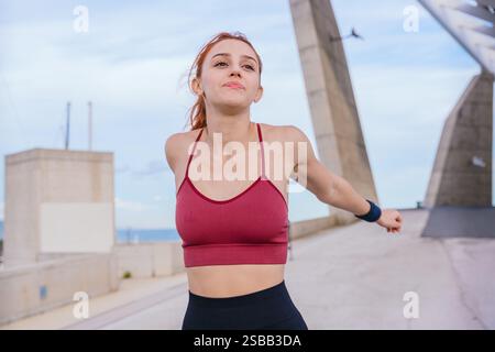 Sportliche junge Frau, die Arme im Freien in der städtischen Umwelt streckt Stockfoto