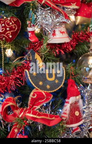 Ein Schaukelpferd, das einen weihnachtsbaum mit Kugeln, Flocken und Elfen dekoriert. Stockfoto