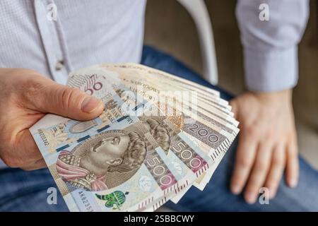 Polen Geld. Selbstbewusster Geschäftsmann, der seine Hand mit polnischen Banknoten hält. Viel Bargeld, 200 und 500 Zloty. Finanzgeschäftskonzept Stockfoto