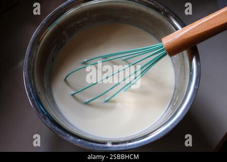 Mischen der Zutaten in einer Edelstahlschale mit dem Handquirl für die Herstellung von rissolarer Haut. Stockfoto