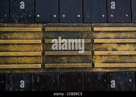 Ein Blick von oben auf den strukturierten gelben Braille-Block und den taktilen Pflaster für blindes Handicap. Perfekt für grafische Ressourcen, Werbung, Hintergrund oder Hintergrundbilder Stockfoto