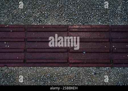 Eine Ansicht aus dem oberen Winkel des strukturierten roten Braille-Blocks, taktiler Pflaster für blindes Handicap. Perfekt für grafische Ressourcen, Werbung, Hintergrund oder Hintergrundbilder Stockfoto
