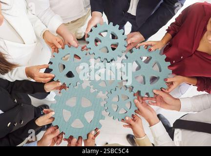 Nahaufnahme des Teams, das die Zahnräder in Einem Kreis zusammenhält Stockfoto