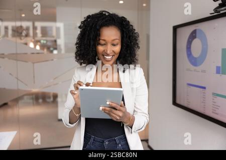 Positive, schöne afrikanische Geschäftsfrau, die am Finanzmarketing-Bericht arbeitet Stockfoto